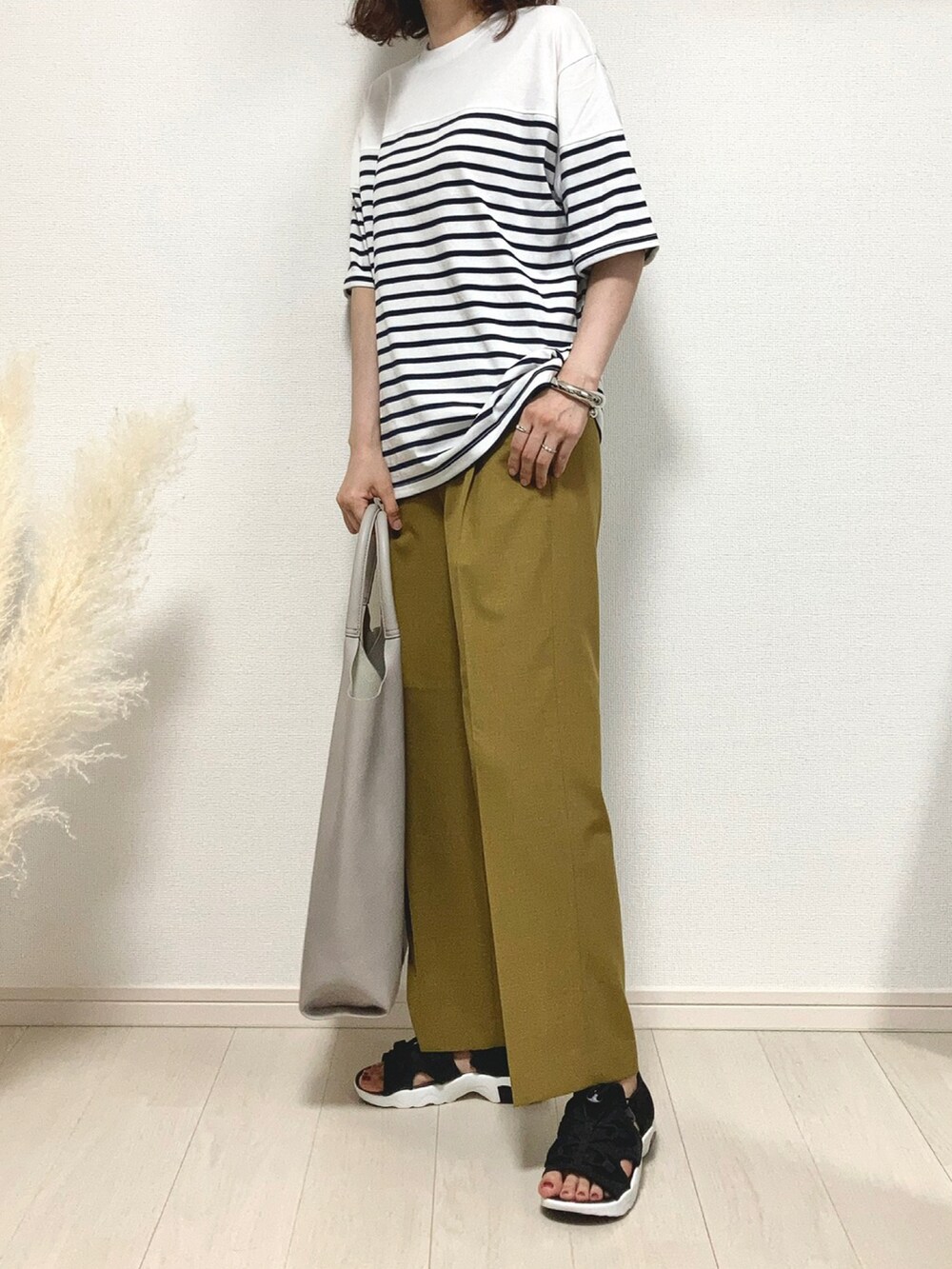 ホワイト系のTシャツ/カットソー、イエロー系のスラックス、ブラック系のサンダルを着用したレディースの夏コーディネートの3枚目の写真