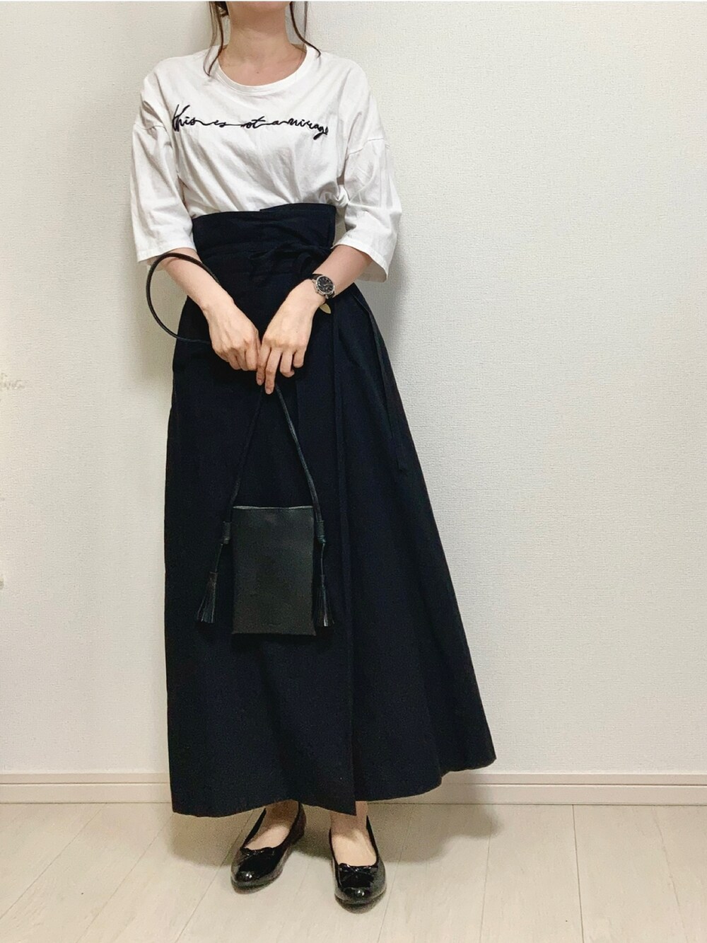 グリーン系のニット/セーター、ホワイト系のTシャツ/カットソー、ブラック系のスカートを着用したレディースの春コーディネートの4枚目の写真