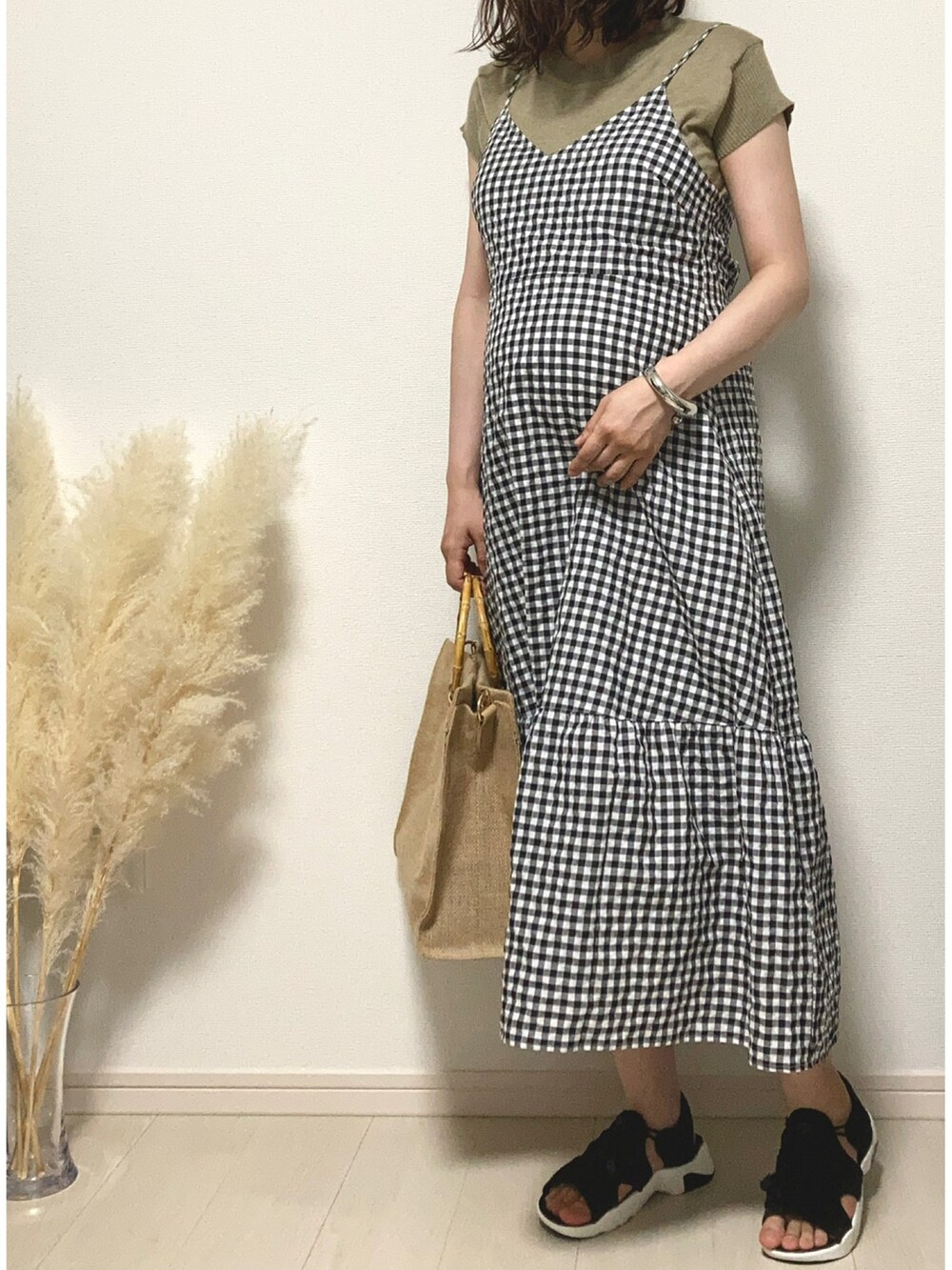 ブラック系のワンピース、ベージュ系のハンドバッグ、ブラック系のサンダルを着用したレディースの夏コーディネートの3枚目の写真