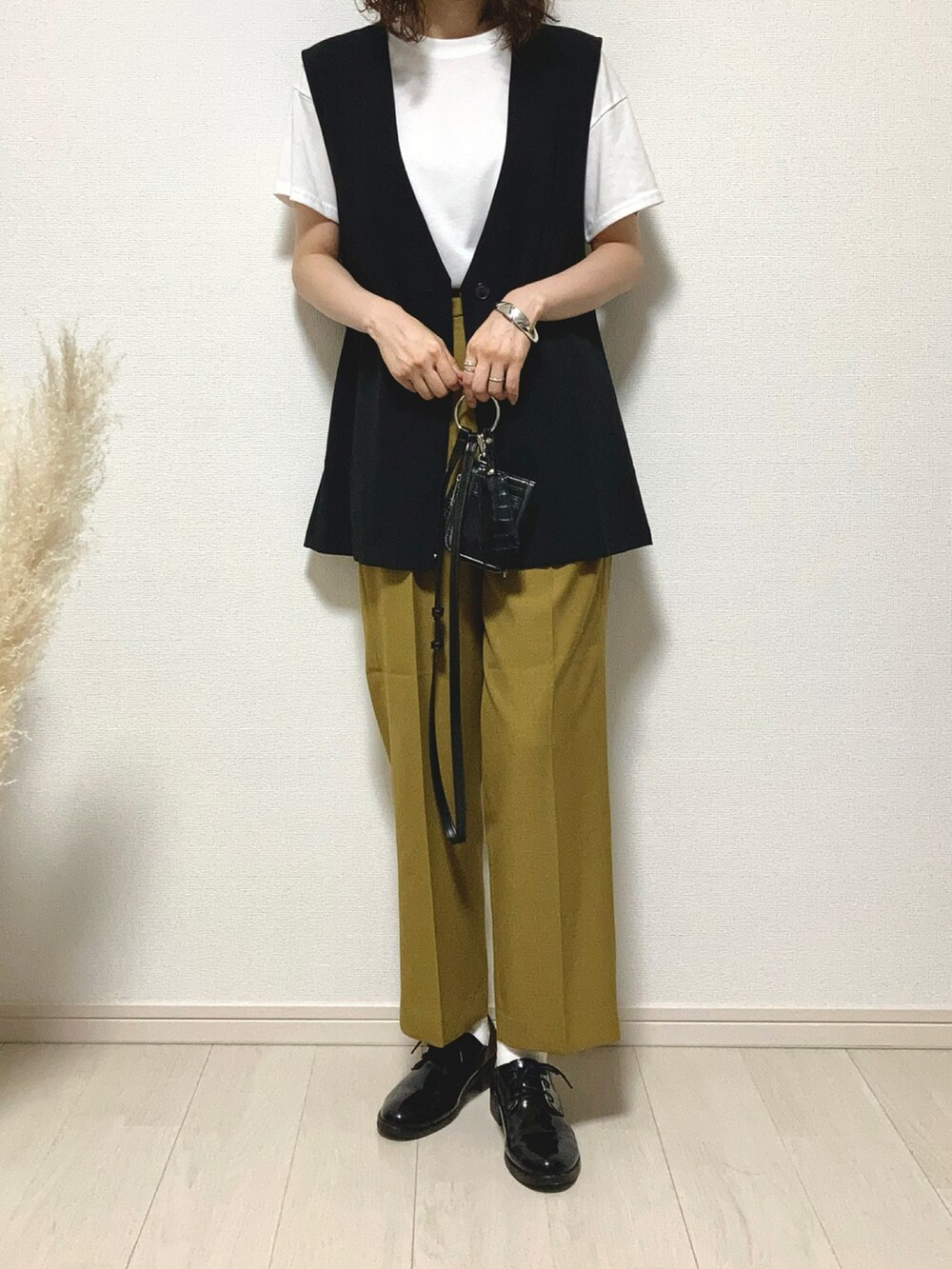 ブラック系のベスト、イエロー系のスラックス、ブラック系のドレスシューズを着用したレディースの夏コーディネートの2枚目の写真