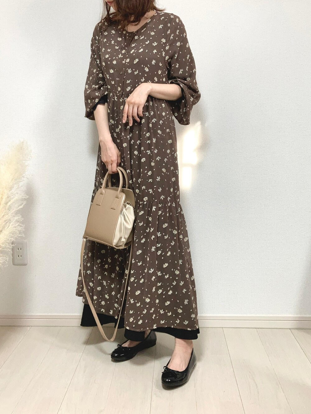 ベージュ系のトレンチコート、ブラウン系のワンピース、ベージュ系のショルダーバッグを着用したレディースの秋コーディネートの2枚目の写真
