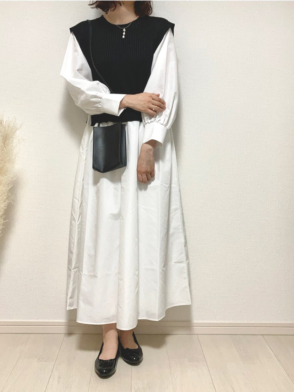 ブラック系のワンピース、ブラック系のパンプス、ブラック系のショルダーバッグを着用したレディースの春コーディネートの2枚目の写真