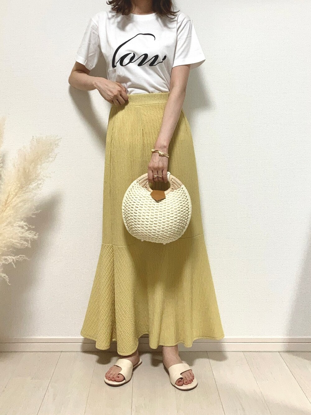 ホワイト系のTシャツ/カットソー、イエロー系のスカート、ホワイト系のかごバッグを着用したレディースの夏コーディネートの2枚目の写真