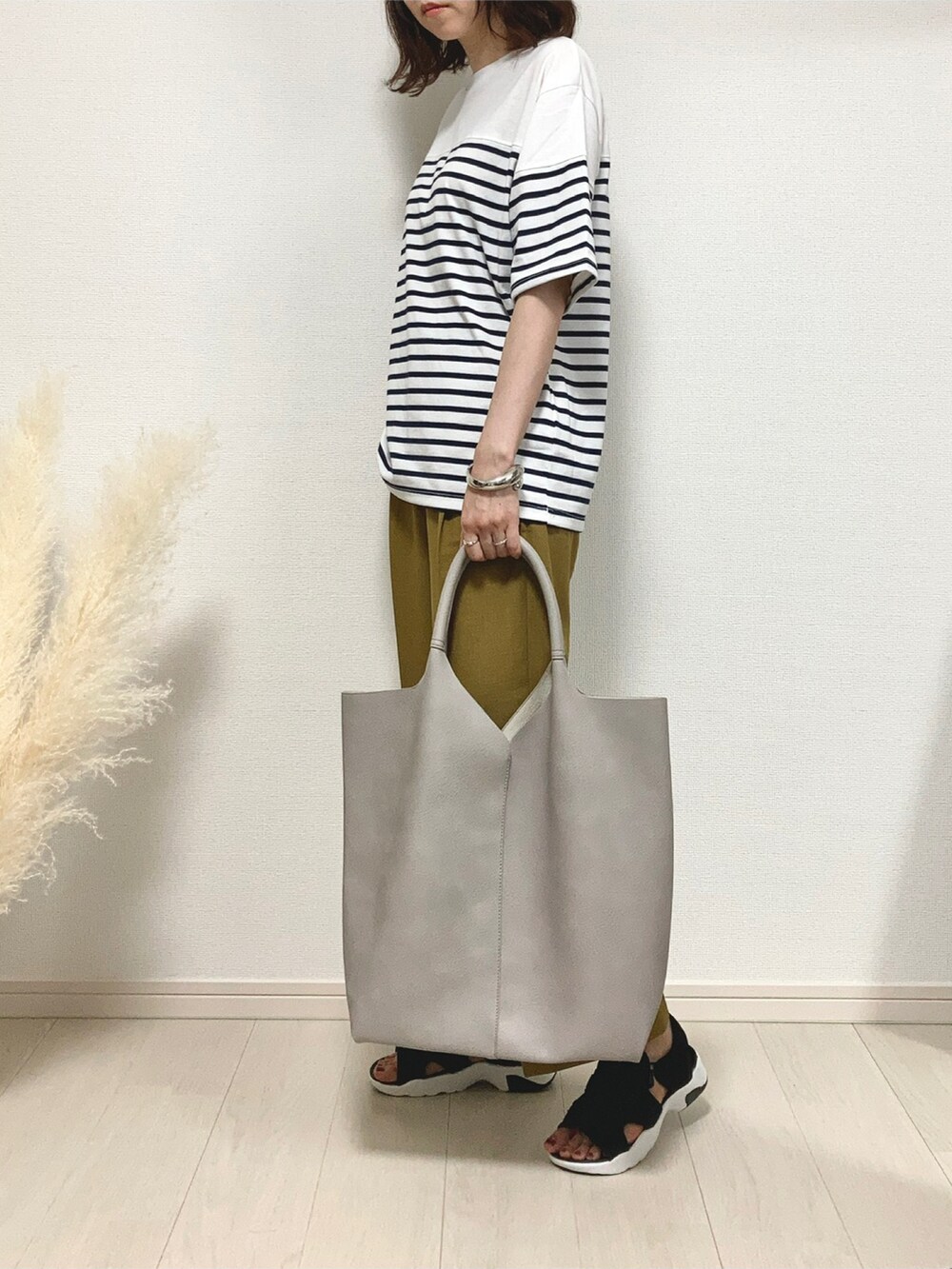 ホワイト系のTシャツ/カットソー、イエロー系のスラックス、ブラック系のサンダルを着用したレディースの夏コーディネートの2枚目の写真