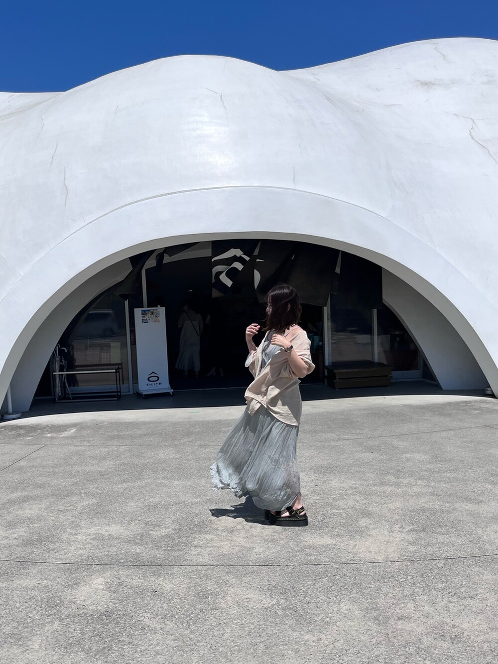 グリーン系のワンピース、ブラック系のサンダル、ベージュ系のシャツ/ブラウスを着用したレディースの夏コーディネートの2枚目の写真