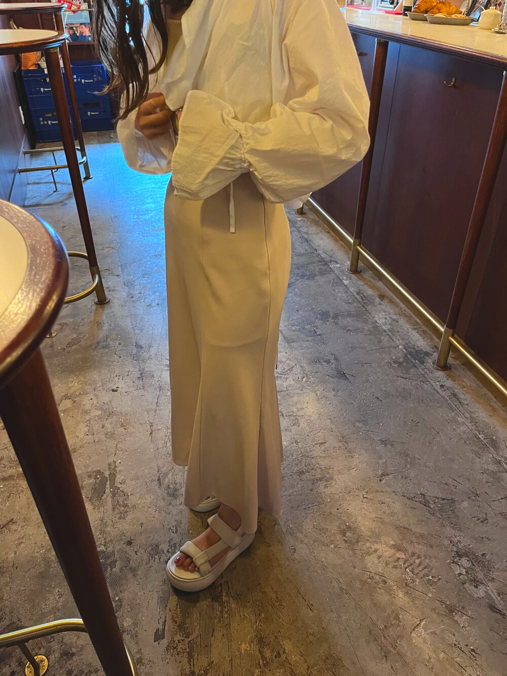 ベージュ系のスカート、ホワイト系のシャツ/ブラウス、ベージュ系の長傘を着用したレディースの夏コーディネートの2枚目の写真