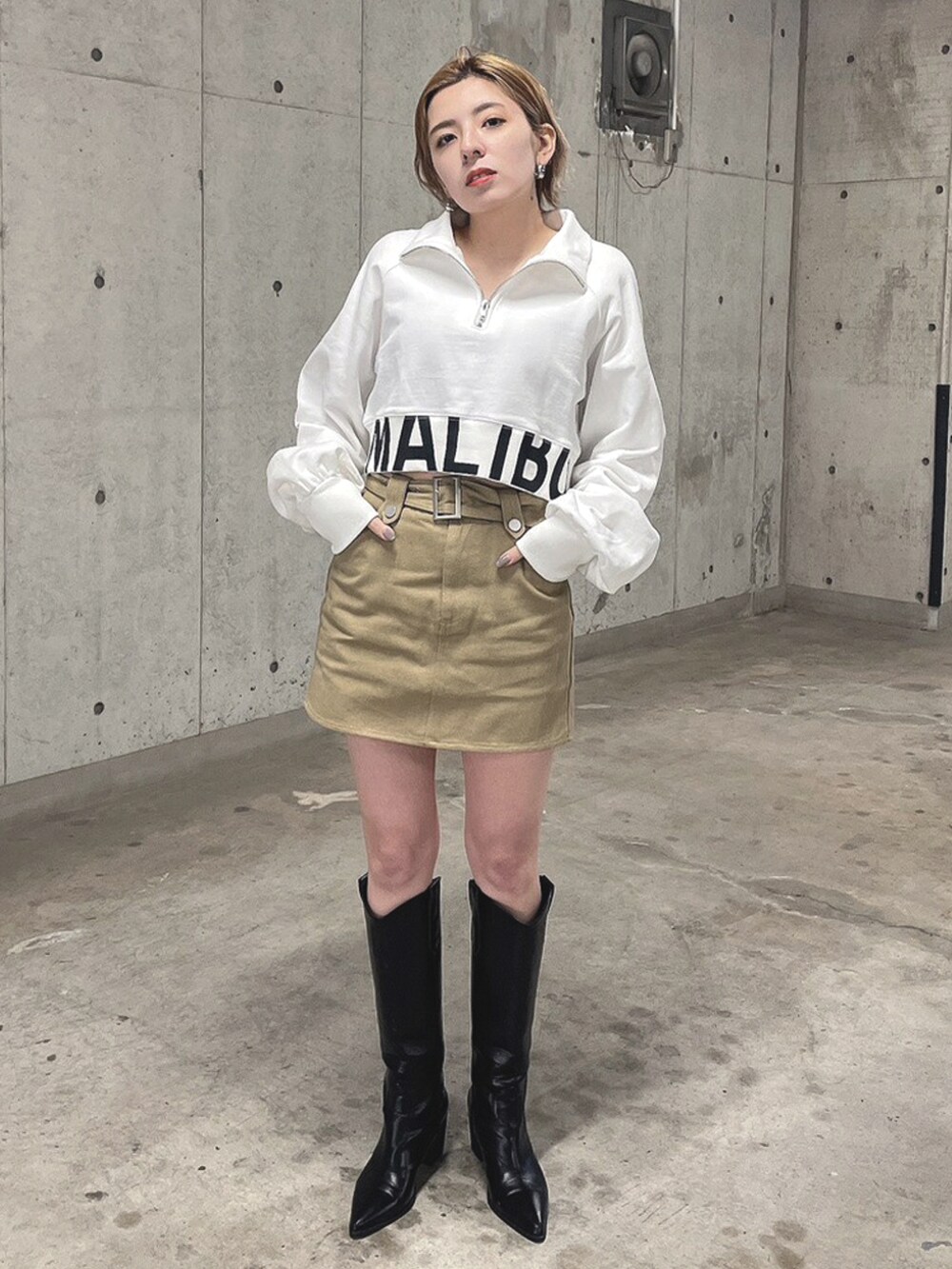 ホワイト系のTシャツ/カットソー、ベージュ系のスカート、ブラック系のブーツを着用したレディースの春コーディネートの2枚目の写真