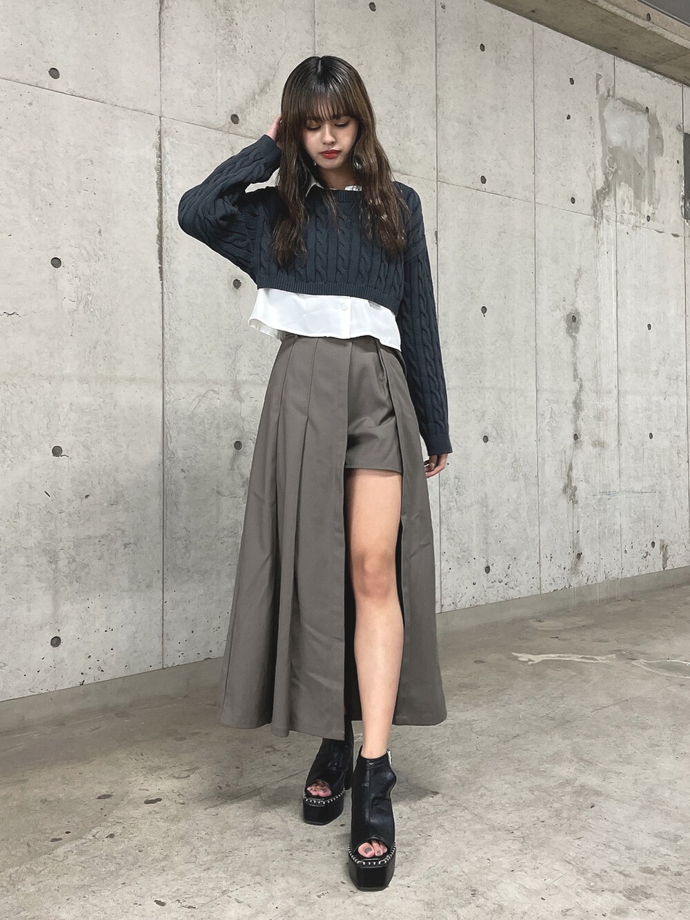 ブラック系のニット/セーター、グレー系のスカート、ブラック系のブーツを着用したレディースの冬コーディネートの2枚目の写真