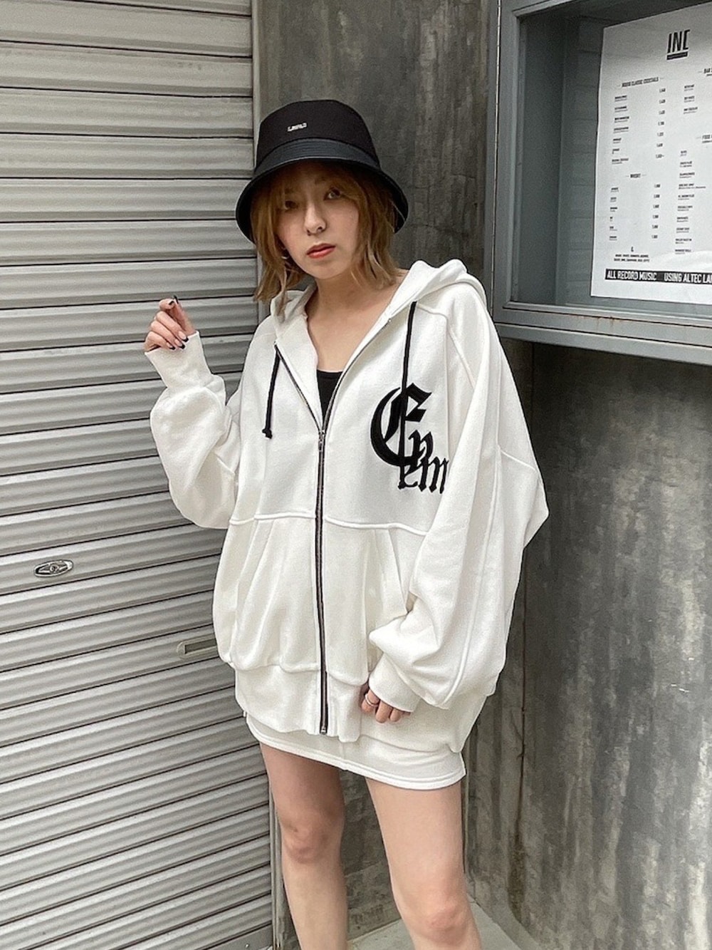 ホワイト系のパーカー、ホワイト系のスカート、ブラック系のその他シューズを着用したレディースの春コーディネートの2枚目の写真