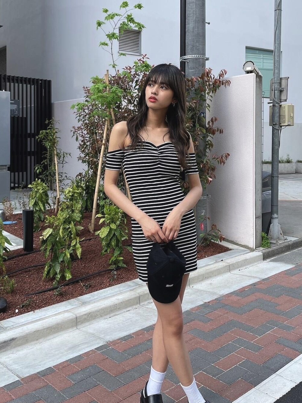 ブラック系のワンピース、ブラック系のサンダル、ブラック系のキャップを着用したレディースの春コーディネートの3枚目の写真