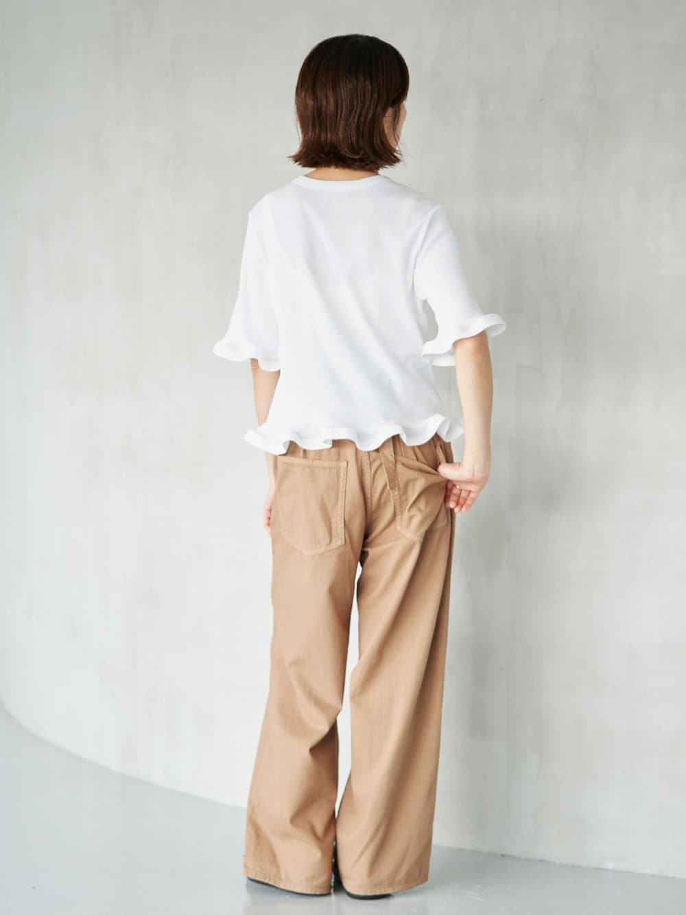 イエロー系のチノパンツ、ホワイト系のTシャツ/カットソー、ブラウン系のサンダルを着用したレディースの夏コーディネートの2枚目の写真