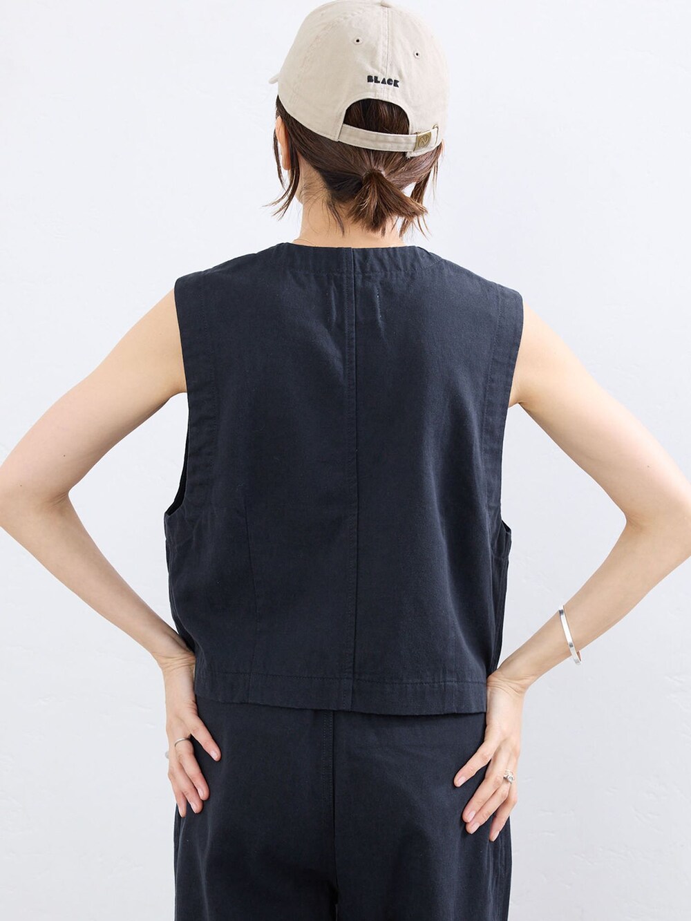 ブルー系のベスト、ブルー系のチノパンツ、ベージュ系のキャップを着用したレディースの夏コーディネートの5枚目の写真
