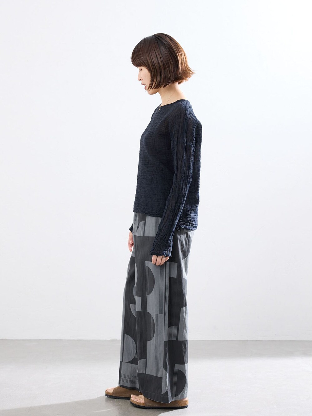 グレー系のその他パンツ、ブラック系のシャツ/ブラウス、ブラウン系のサンダルを着用したレディースの春コーディネートの2枚目の写真
