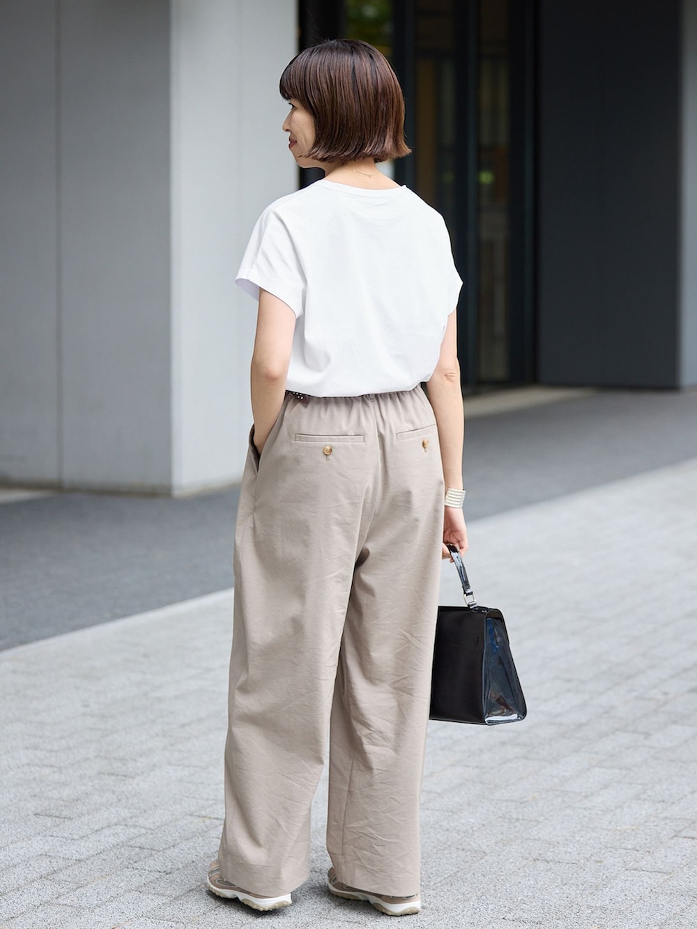 ベージュ系のスラックス、ホワイト系のTシャツ/カットソーを着用したレディースの春コーディネートの3枚目の写真