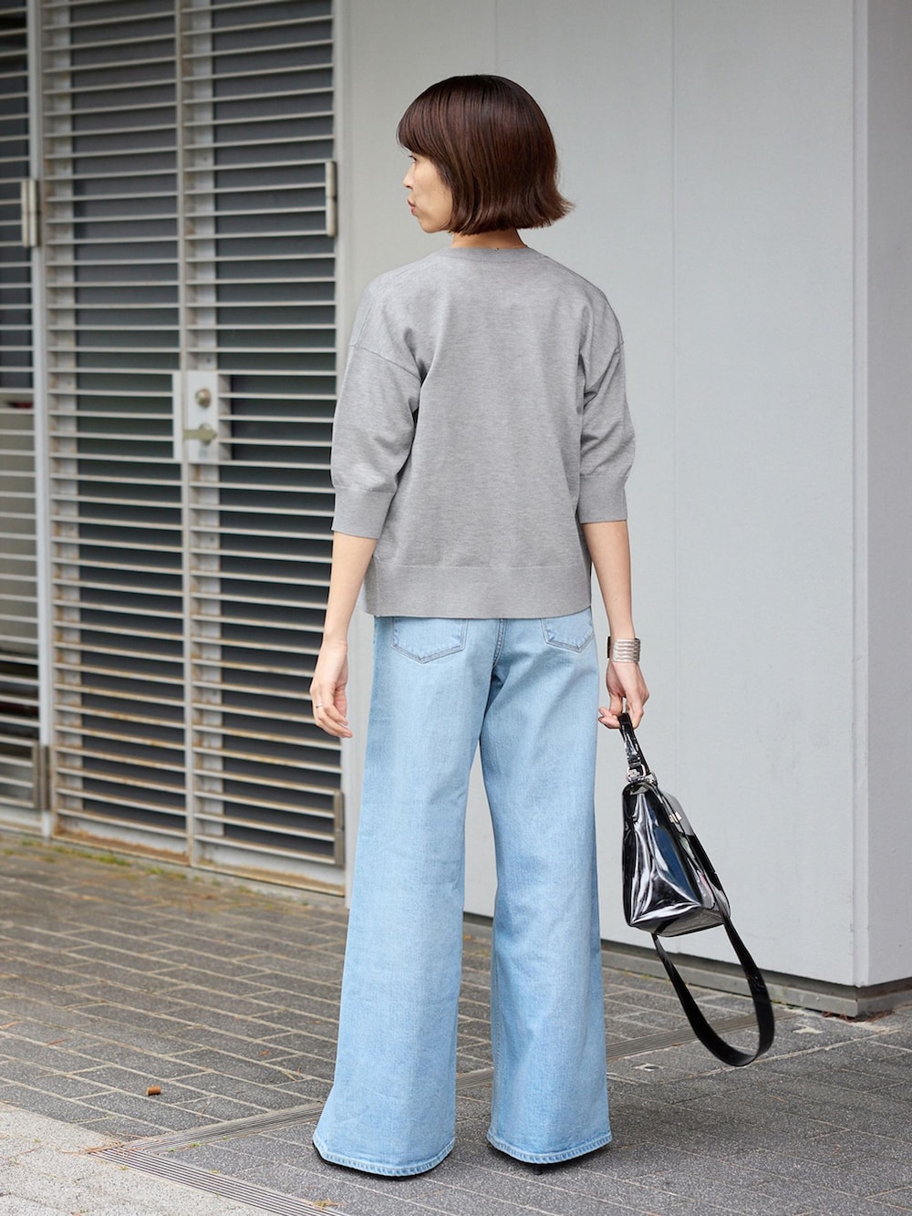 ブルー系のデニムパンツ、ホワイト系のTシャツ/カットソー、グレー系のカーディガン/ボレロを着用したレディースの春コーディネートの2枚目の写真