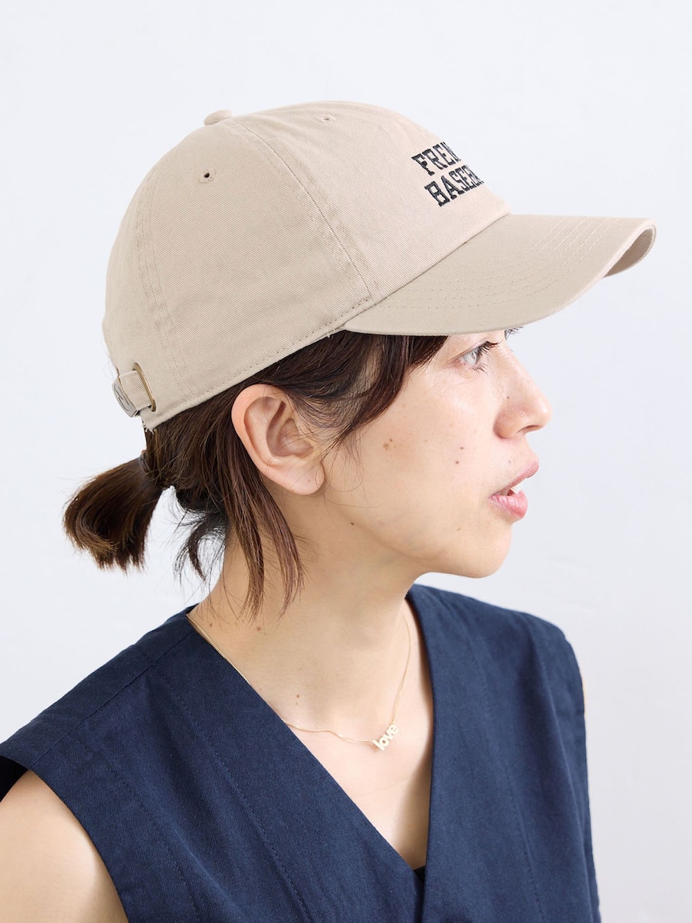 ブルー系のベスト、ブルー系のチノパンツ、ベージュ系のキャップを着用したレディースの夏コーディネートの8枚目の写真