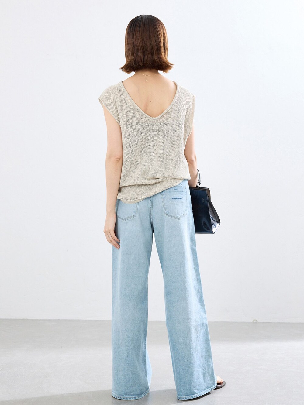 ブルー系のデニムパンツ、ベージュ系のニット/セーターを着用したレディースの春コーディネートの2枚目の写真