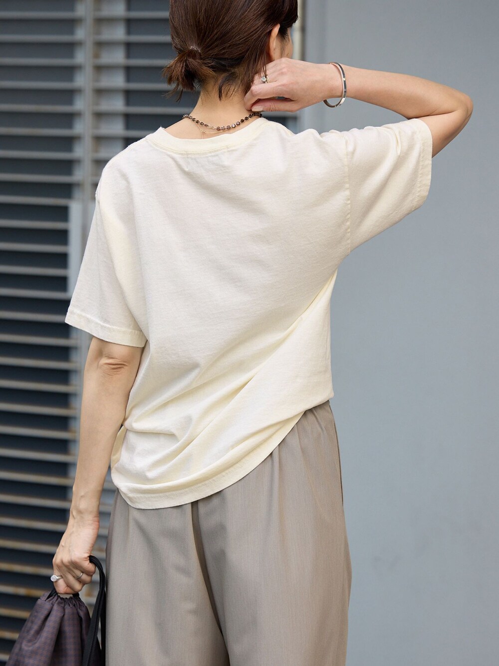 ベージュ系のスラックス、ホワイト系のTシャツ/カットソー、ブラウン系のバックパック/リュックを着用したレディースの夏コーディネートの4枚目の写真
