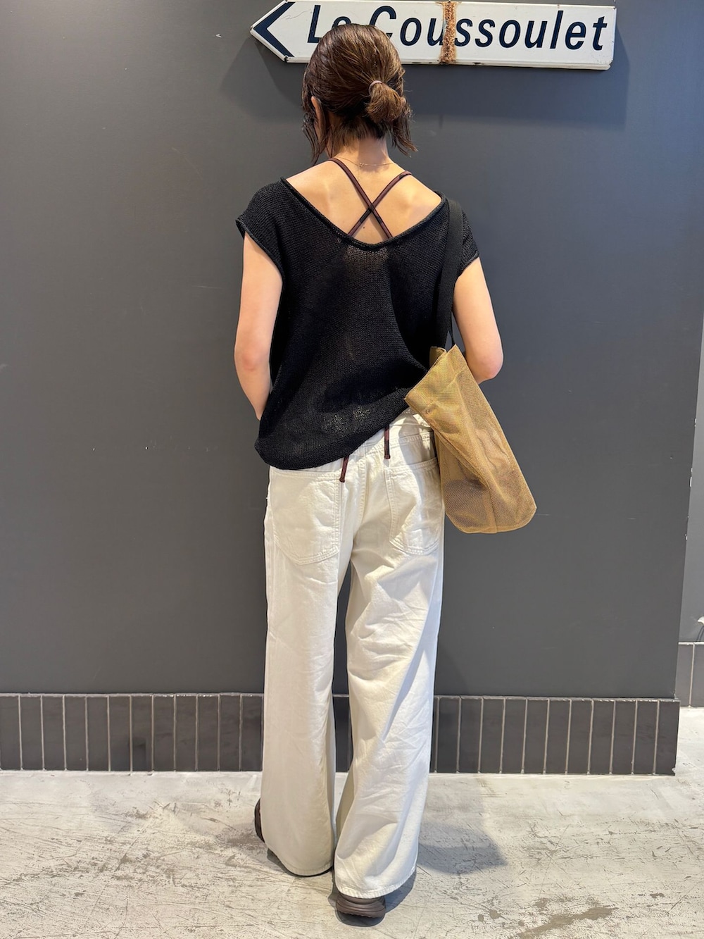 ホワイト系のチノパンツ、ブラック系のニット/セーター、イエロー系のトートバッグを着用したレディースの夏コーディネートの3枚目の写真