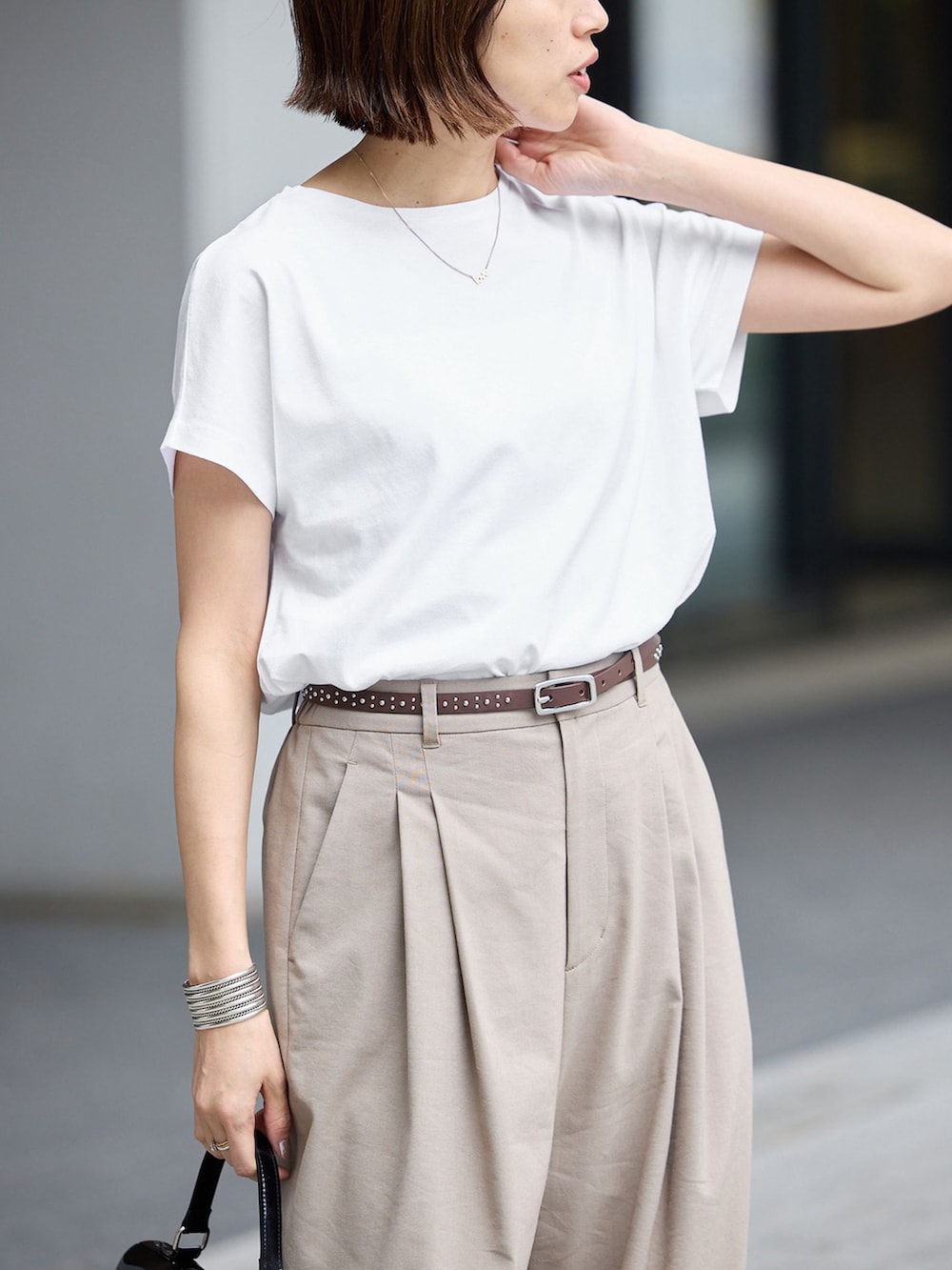 ベージュ系のスラックス、ホワイト系のTシャツ/カットソーを着用したレディースの春コーディネートの4枚目の写真