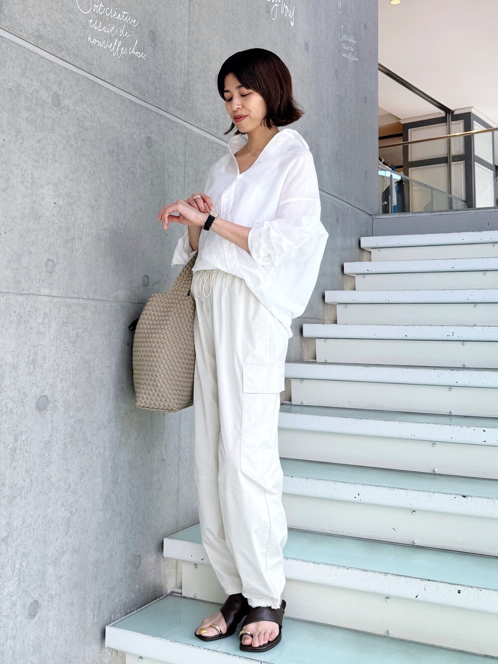 ホワイト系のスラックス、ホワイト系のシャツ/ブラウス、ベージュ系のトートバッグを着用したレディースの春コーディネートの6枚目の写真