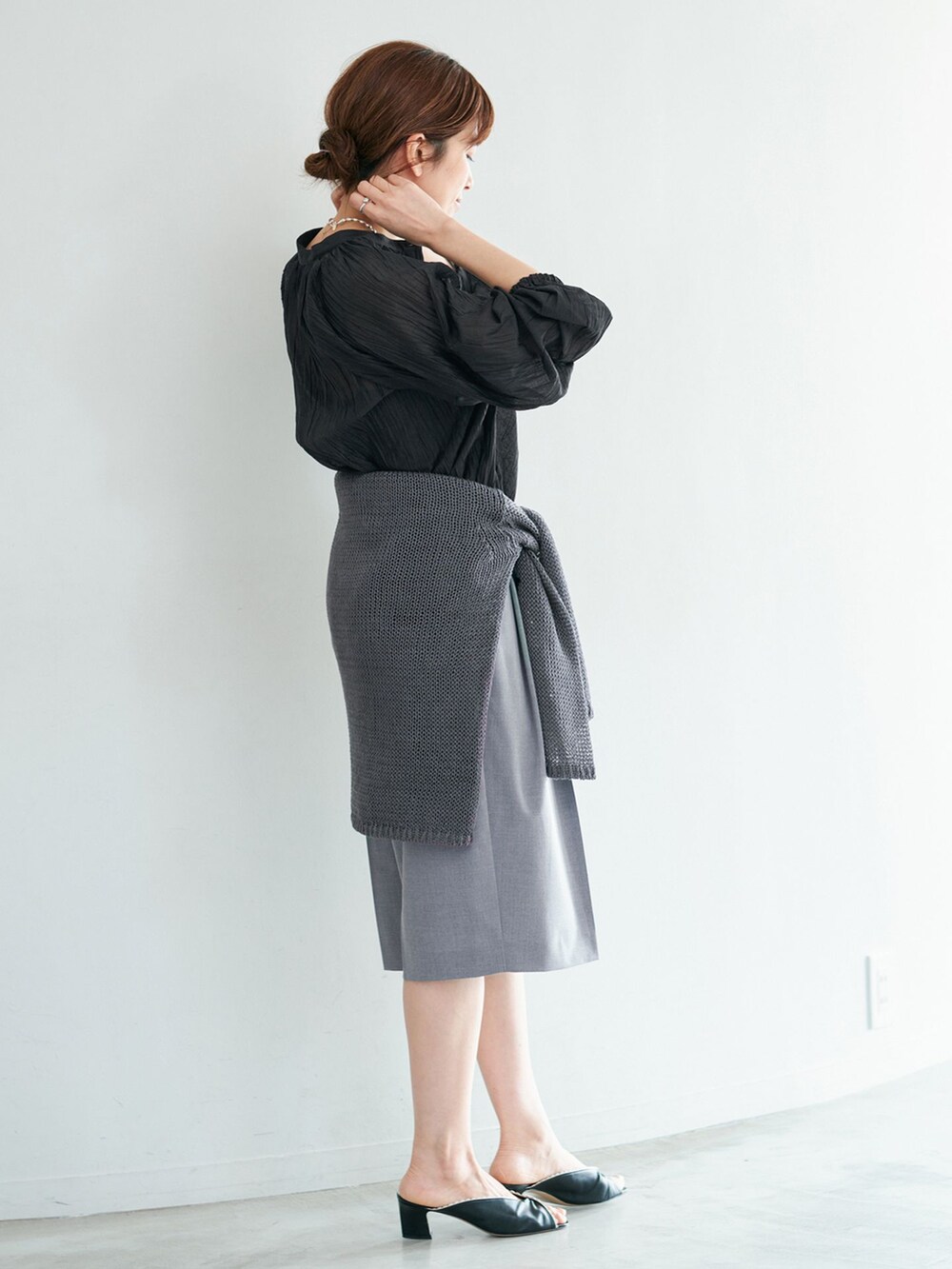 グレー系のその他パンツ、ブラック系のシャツ/ブラウス、グレー系のニット/セーターを着用したレディースの冬コーディネートの2枚目の写真