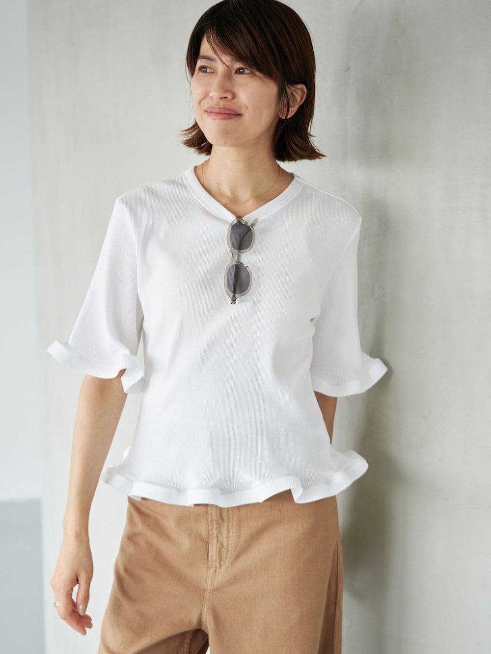 イエロー系のチノパンツ、ホワイト系のTシャツ/カットソー、ブラウン系のサンダルを着用したレディースの夏コーディネートの3枚目の写真
