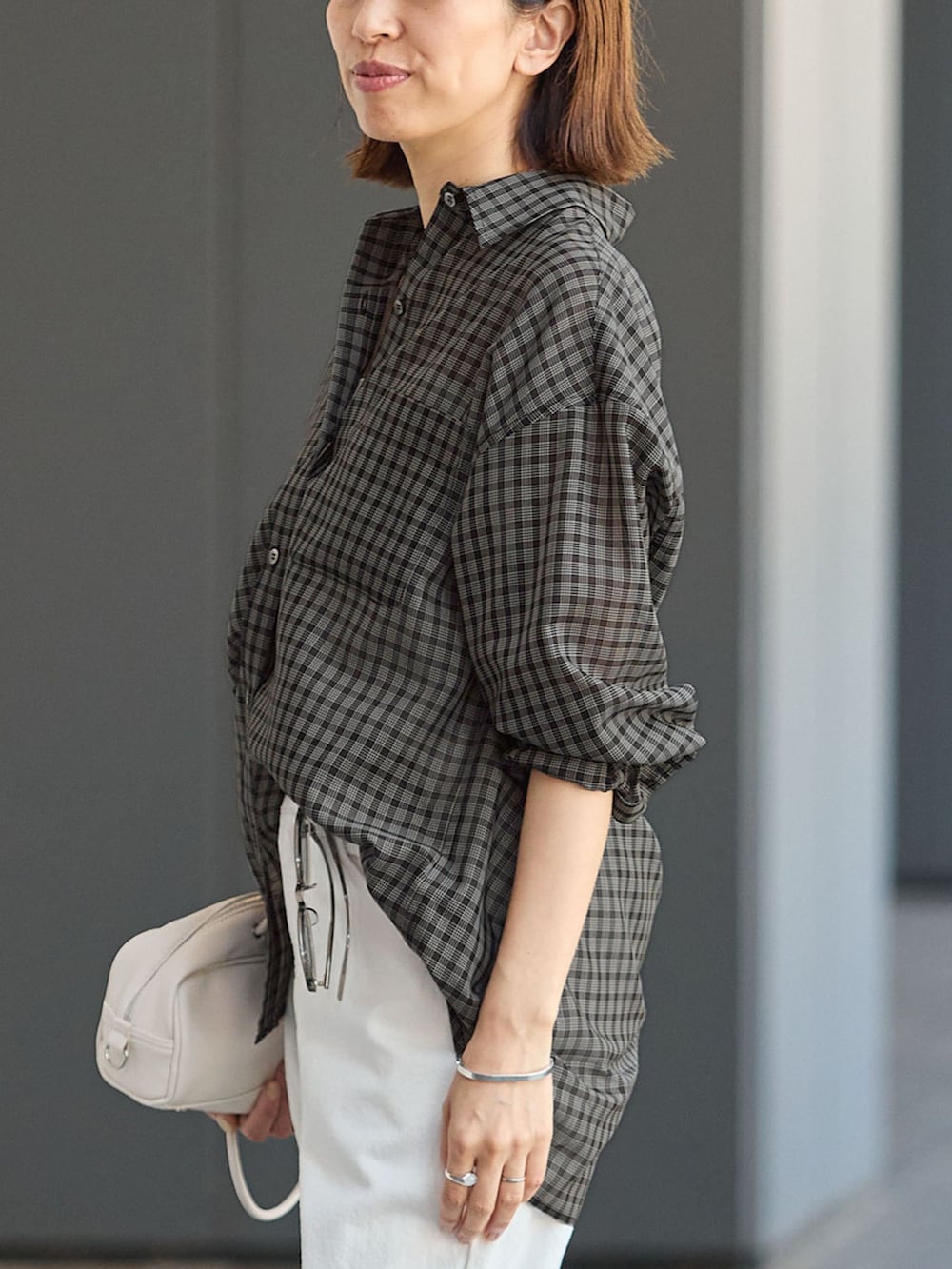 ホワイト系のデニムパンツ、ブラック系のシャツ/ブラウス、ホワイト系のショルダーバッグを着用したレディースの夏コーディネートの5枚目の写真
