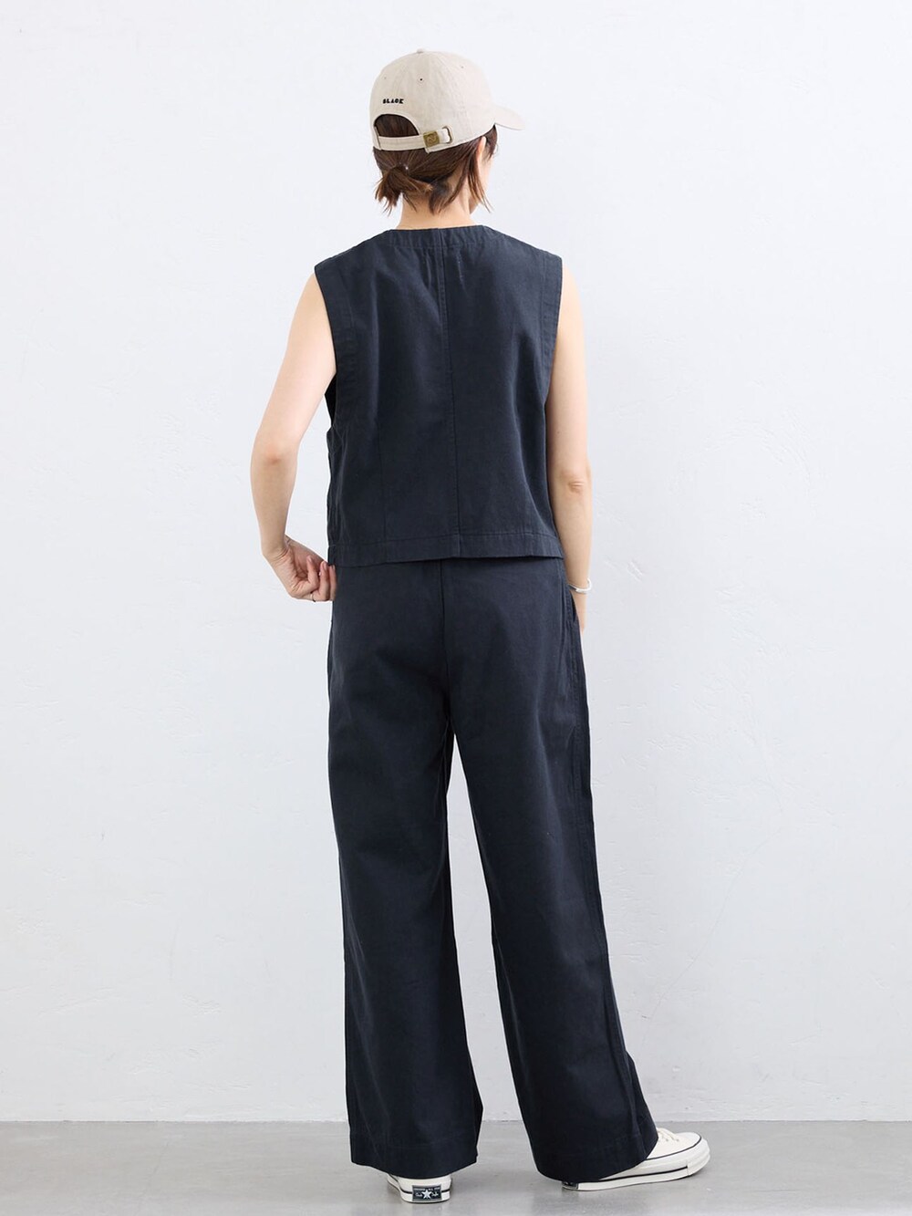 ブルー系のベスト、ブルー系のチノパンツ、ベージュ系のキャップを着用したレディースの夏コーディネートの3枚目の写真
