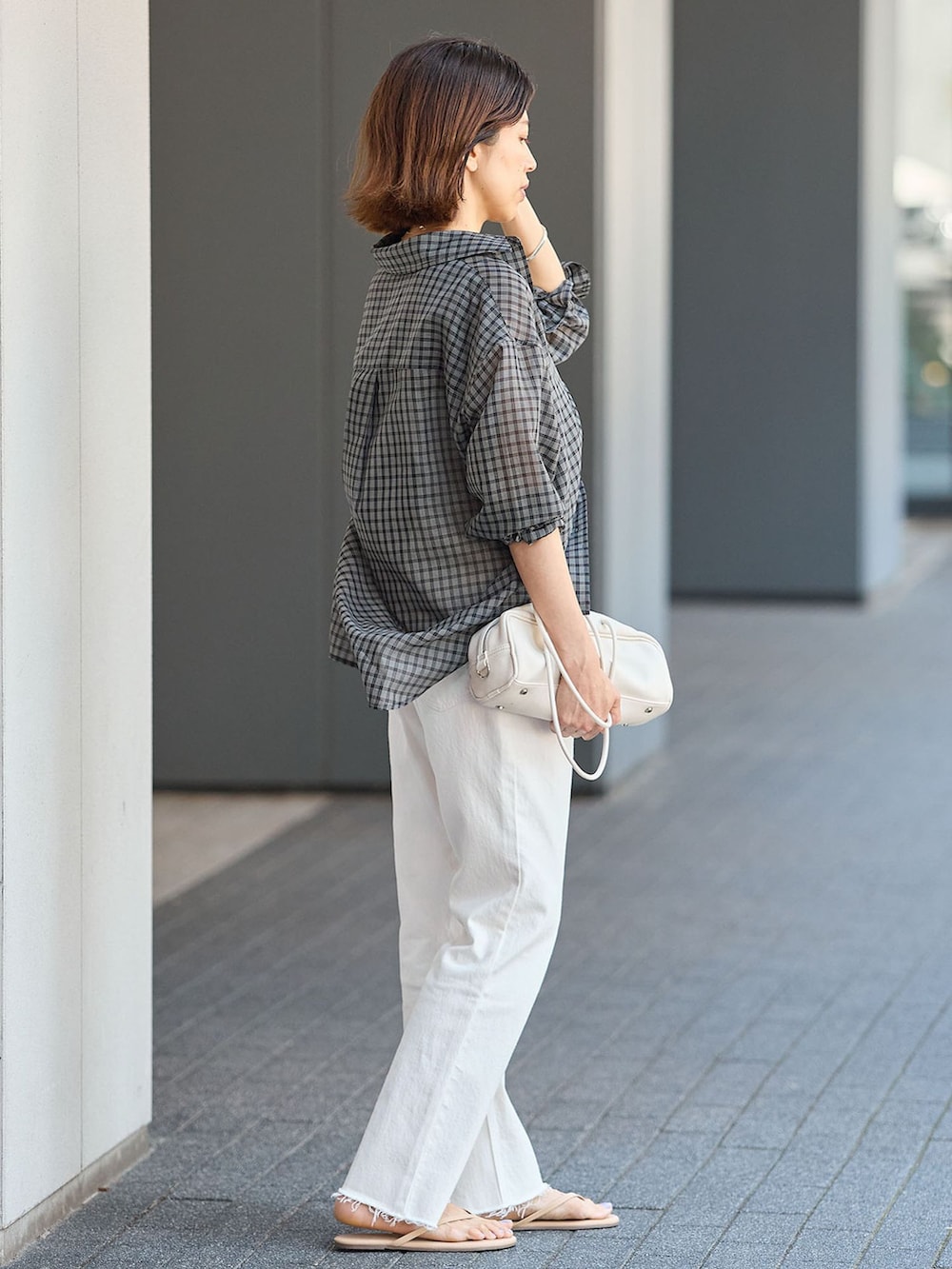 ホワイト系のデニムパンツ、ブラック系のシャツ/ブラウス、ホワイト系のショルダーバッグを着用したレディースの夏コーディネートの2枚目の写真