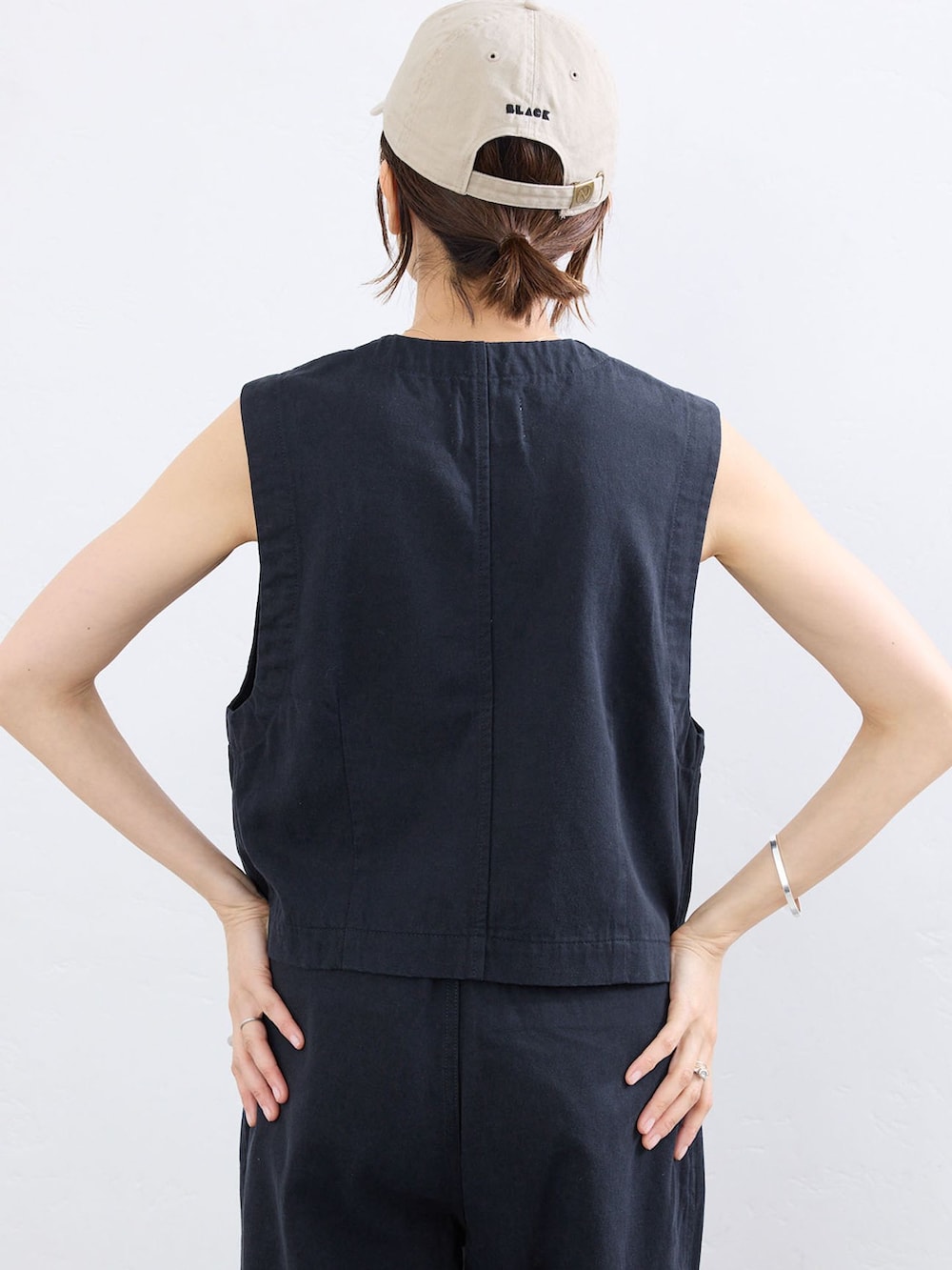 ブルー系のベスト、ブルー系のチノパンツ、ベージュ系のキャップを着用したレディースの夏コーディネートの5枚目の写真