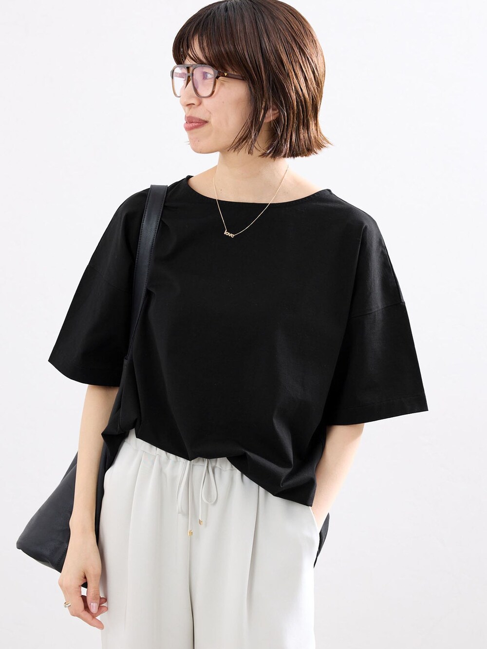 ベージュ系のその他パンツ、ブラック系のTシャツ/カットソー、ブラック系のショルダーバッグを着用したレディースの春コーディネートの4枚目の写真