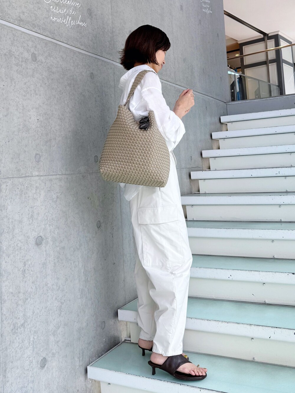 ホワイト系のスラックス、ホワイト系のシャツ/ブラウス、ベージュ系のトートバッグを着用したレディースの春コーディネートの7枚目の写真