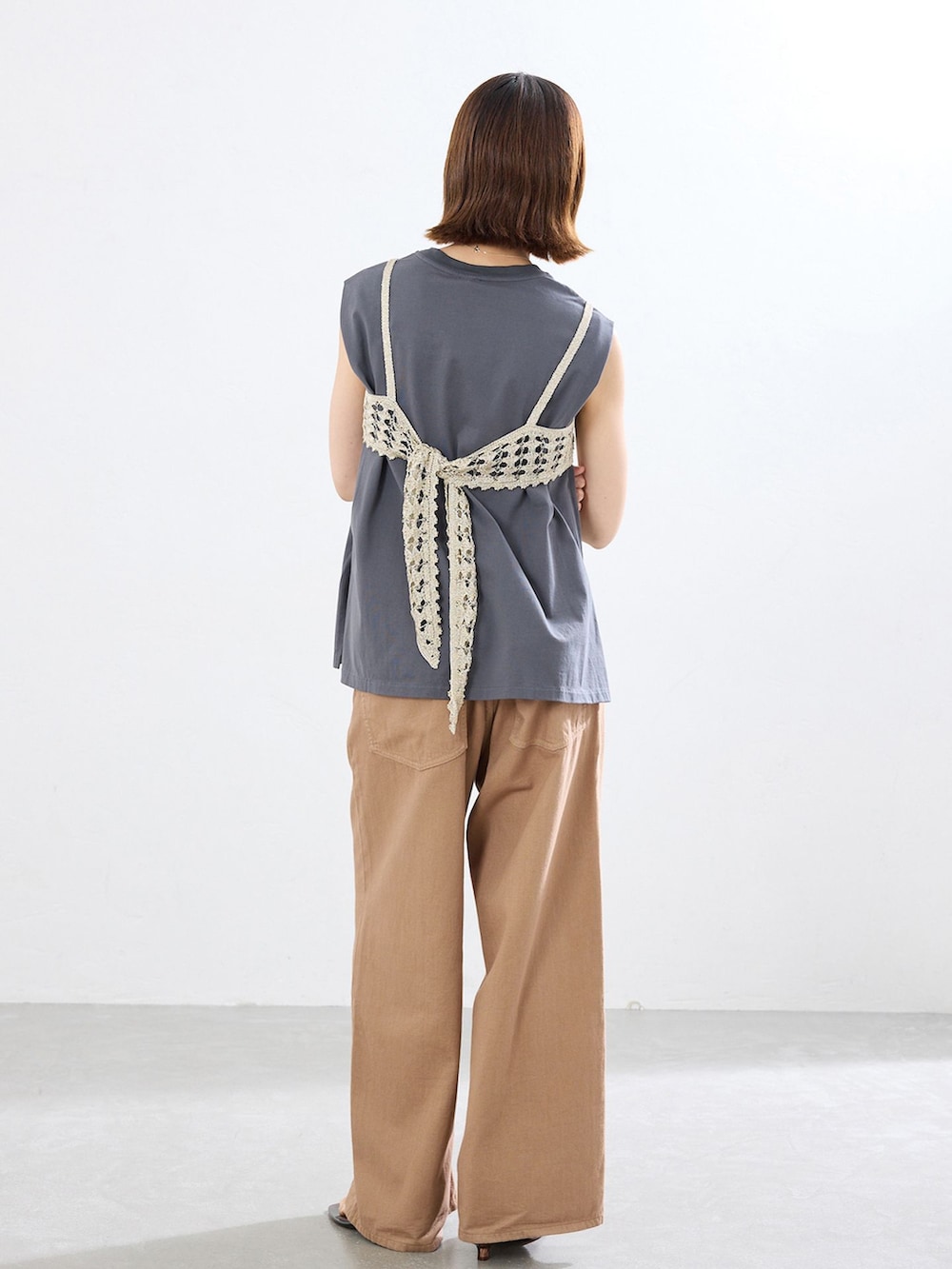 イエロー系のチノパンツ、グレー系のTシャツ/カットソー、ブラウン系のサンダルを着用したレディースの春コーディネートの3枚目の写真