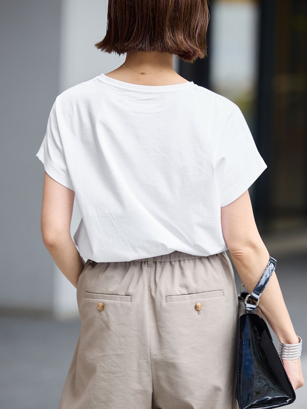ベージュ系のスラックス、ホワイト系のTシャツ/カットソーを着用したレディースの春コーディネートの5枚目の写真