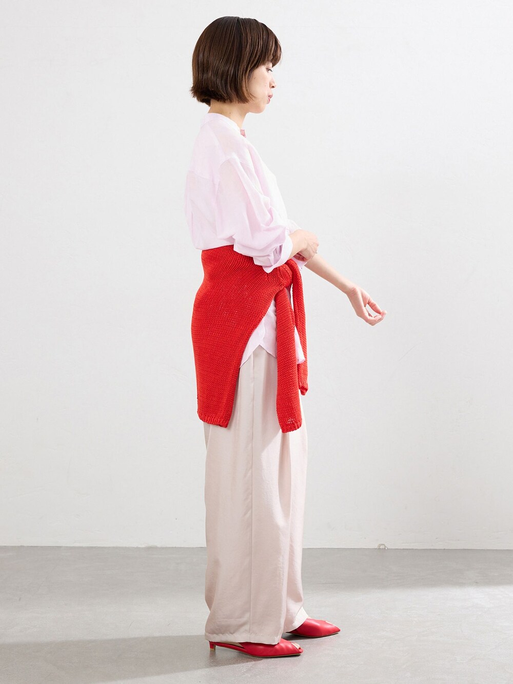 ピンク系のシャツ/ブラウス、レッド系のニット/セーター、レッド系のパンプスを着用したレディースの春コーディネートの2枚目の写真