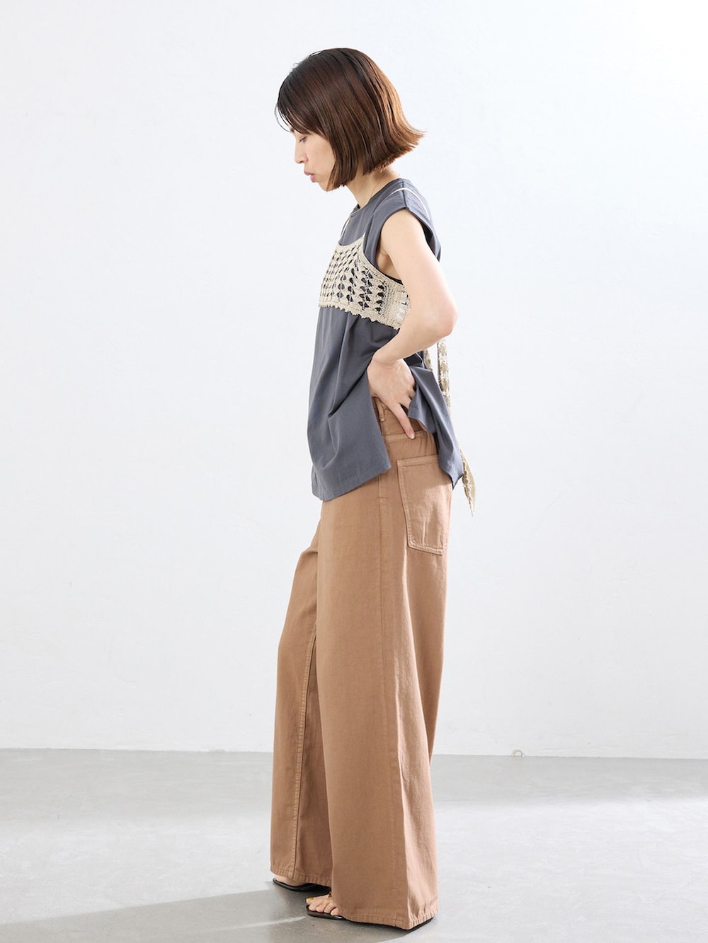 イエロー系のチノパンツ、グレー系のTシャツ/カットソー、ブラウン系のサンダルを着用したレディースの春コーディネートの2枚目の写真