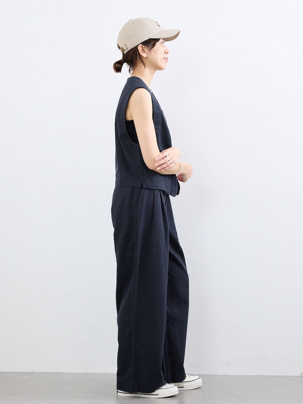 ブルー系のベスト、ブルー系のチノパンツ、ベージュ系のキャップを着用したレディースの夏コーディネートの2枚目の写真