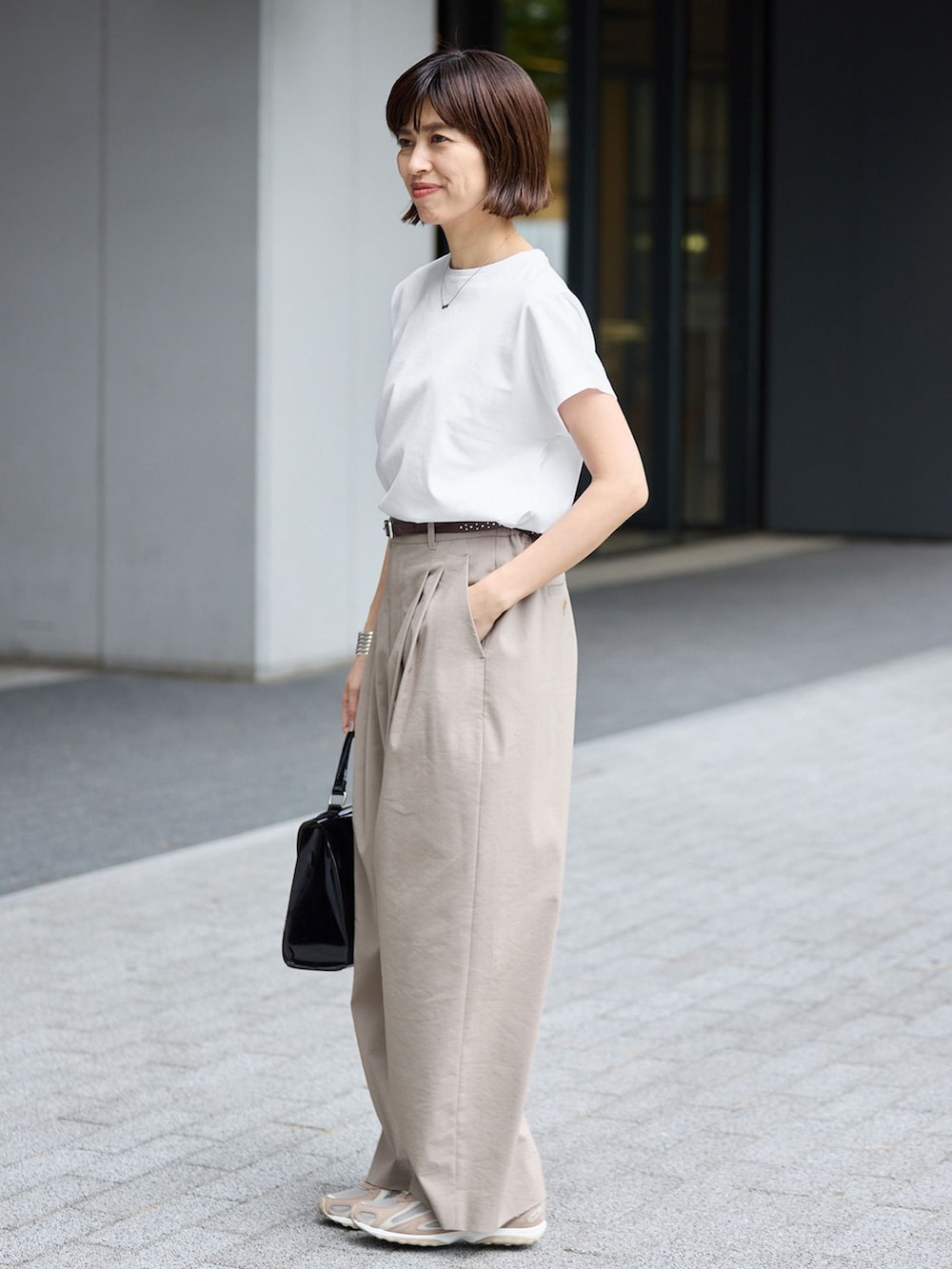 ベージュ系のスラックス、ホワイト系のTシャツ/カットソーを着用したレディースの春コーディネートの2枚目の写真