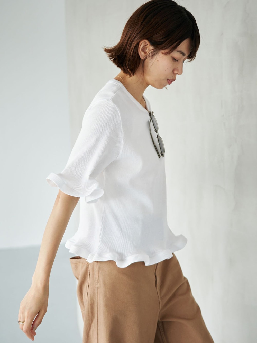イエロー系のチノパンツ、ホワイト系のTシャツ/カットソー、ブラウン系のサンダルを着用したレディースの夏コーディネートの4枚目の写真