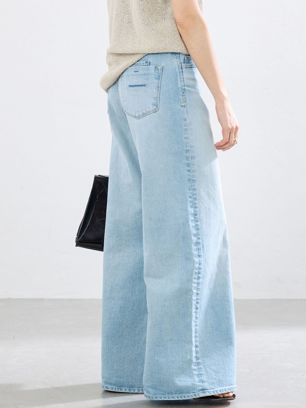ブルー系のデニムパンツ、ベージュ系のニット/セーターを着用したレディースの春コーディネートの4枚目の写真