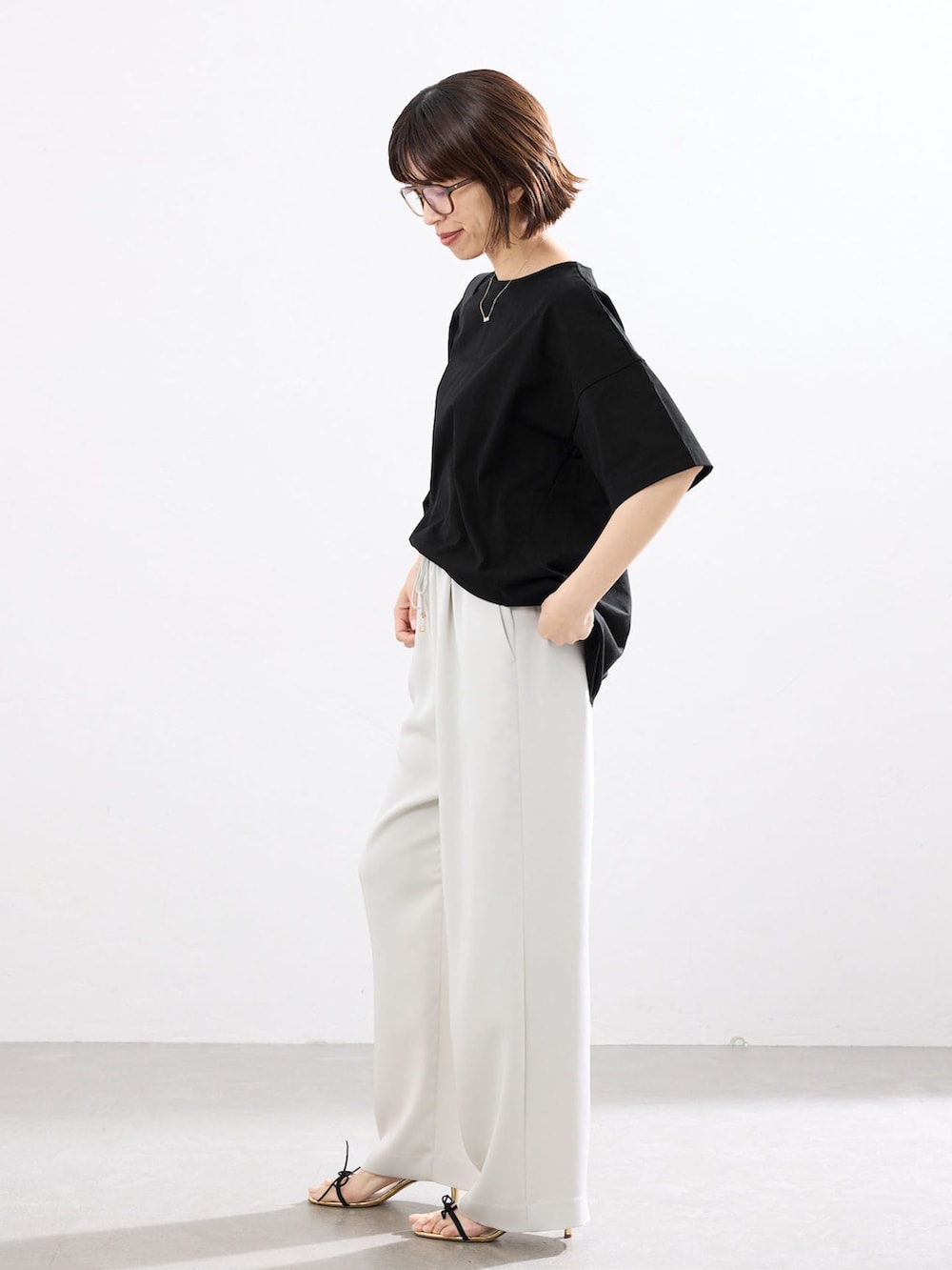 ベージュ系のその他パンツ、ブラック系のTシャツ/カットソー、ブラック系のショルダーバッグを着用したレディースの春コーディネートの2枚目の写真