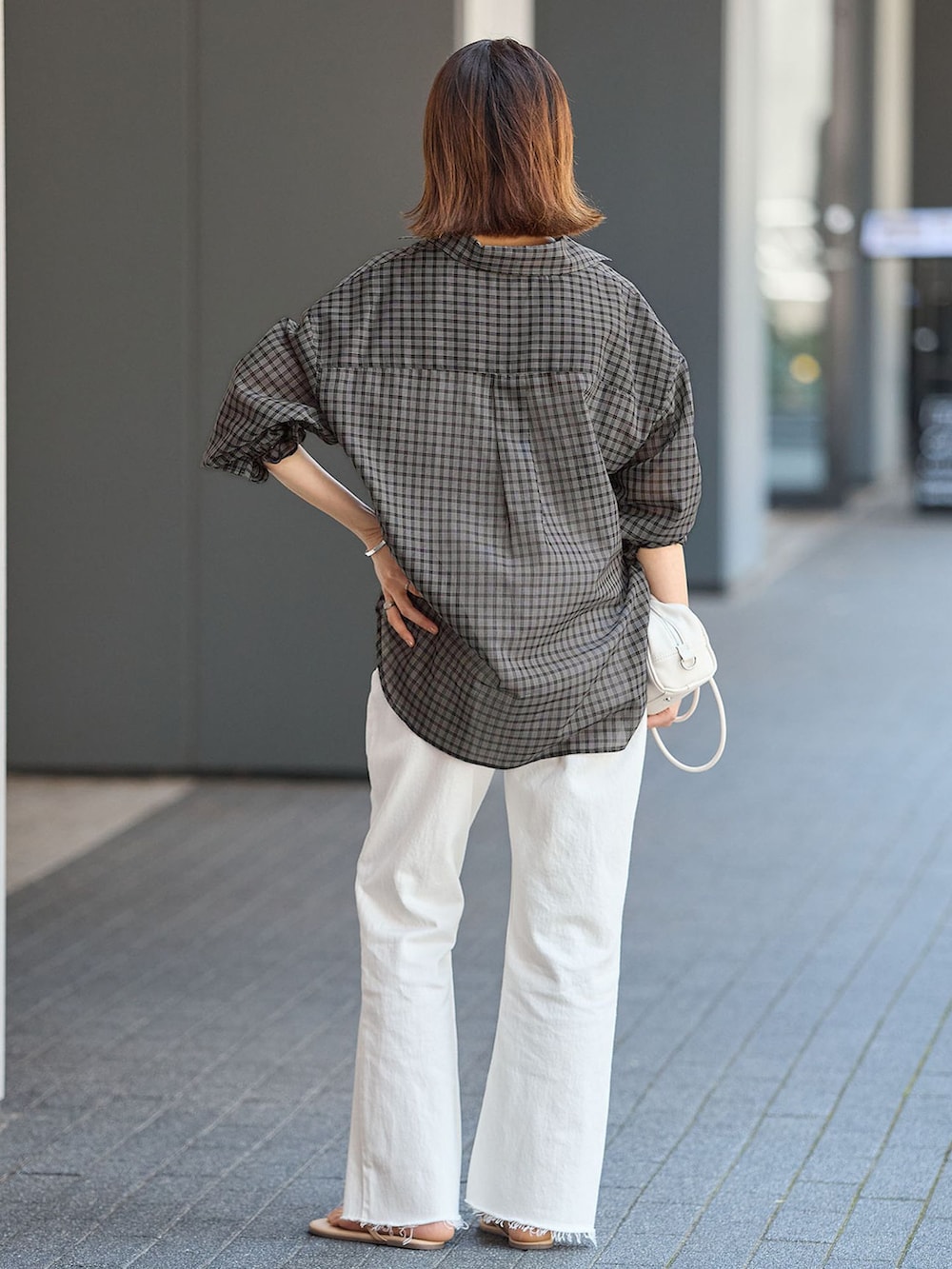 ホワイト系のデニムパンツ、ブラック系のシャツ/ブラウス、ホワイト系のショルダーバッグを着用したレディースの夏コーディネートの3枚目の写真