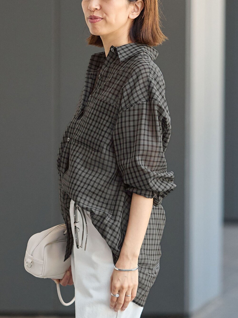 ホワイト系のデニムパンツ、ブラック系のシャツ/ブラウス、ホワイト系のショルダーバッグを着用したレディースの秋コーディネートの5枚目の写真