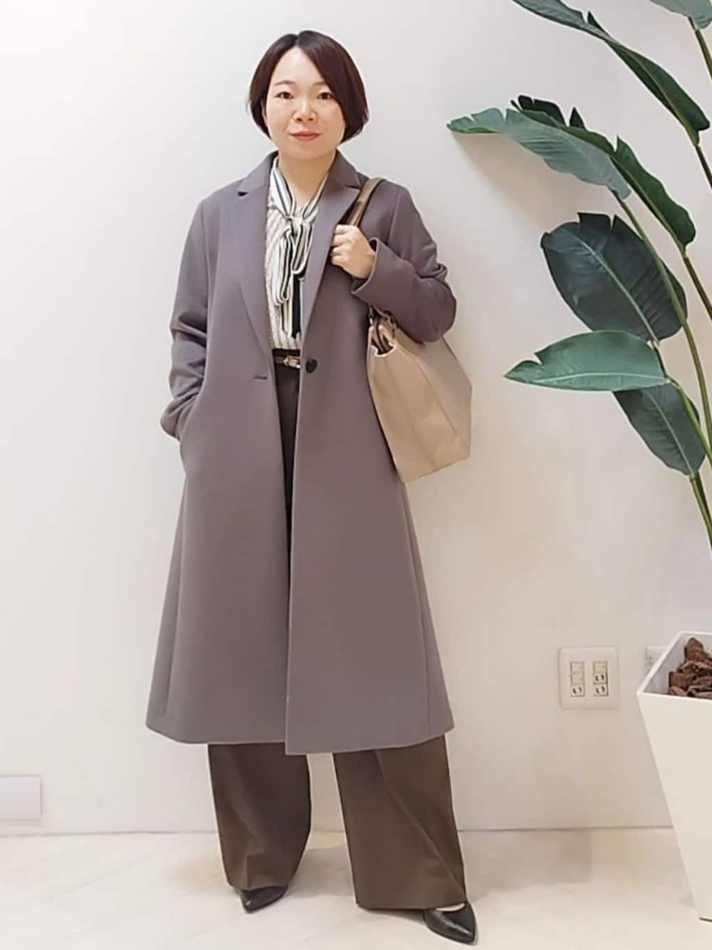 グレー系のチェスターコート、ベージュ系のシャツ/ブラウス、ブラウン系のその他パンツを着用したレディースの冬コーディネートの2枚目の写真