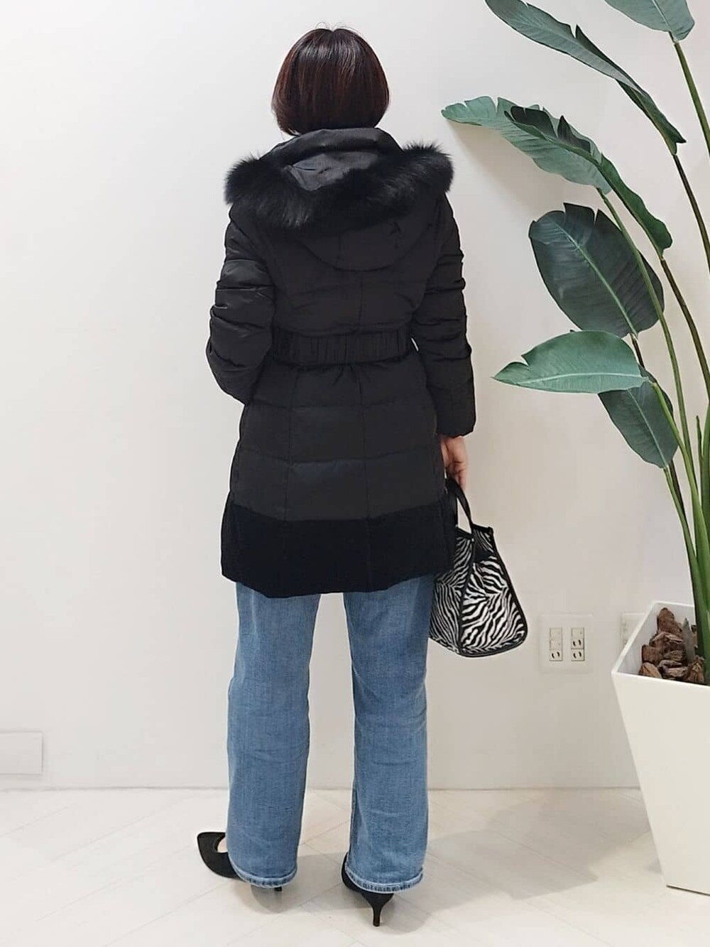 ブラック系のダウンジャケット/コート、ブルー系のニット/セーター、ブルー系のデニムパンツを着用したレディースの冬コーディネートの8枚目の写真