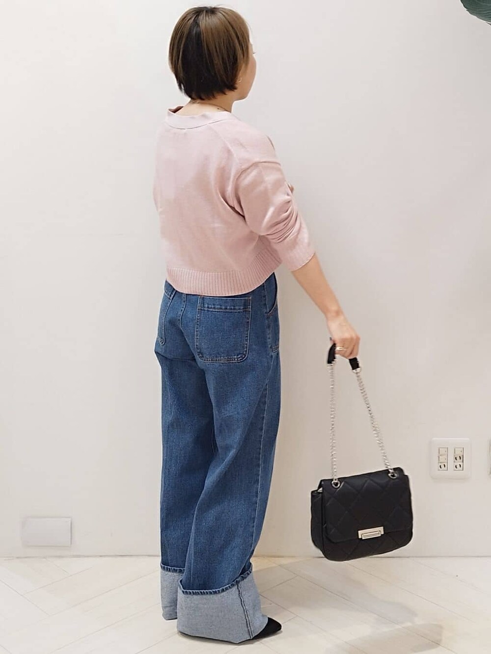 ピンク系のカーディガン/ボレロ、ブルー系のデニムパンツ、ブラック系のショルダーバッグを着用したレディースの冬コーディネートの3枚目の写真
