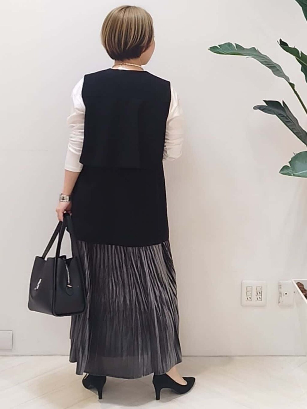 ブラック系のベスト、ホワイト系のTシャツ/カットソー、グレー系のスカートを着用したレディースの冬コーディネートの8枚目の写真