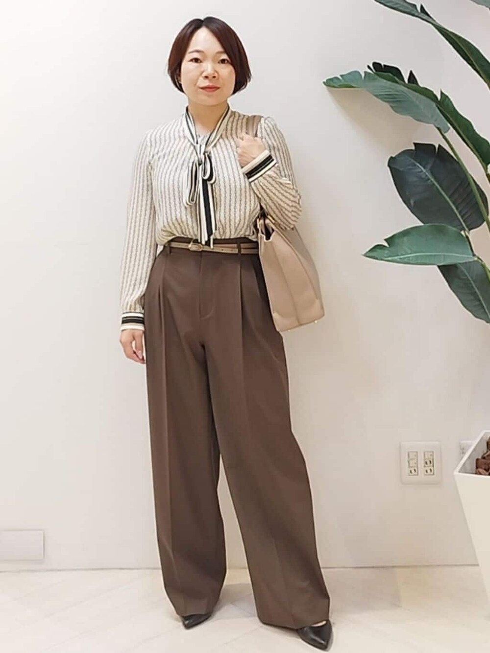 グレー系のチェスターコート、ベージュ系のシャツ/ブラウス、ブラウン系のその他パンツを着用したレディースの冬コーディネートの7枚目の写真