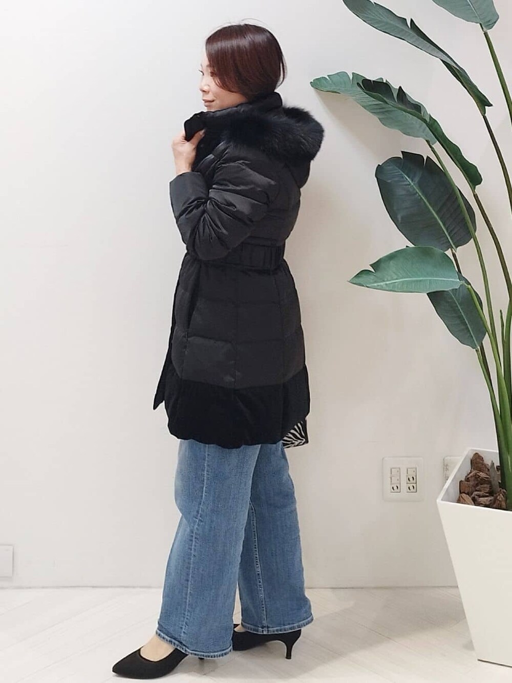 ブラック系のダウンジャケット/コート、ブルー系のニット/セーター、ブルー系のデニムパンツを着用したレディースの冬コーディネートの4枚目の写真